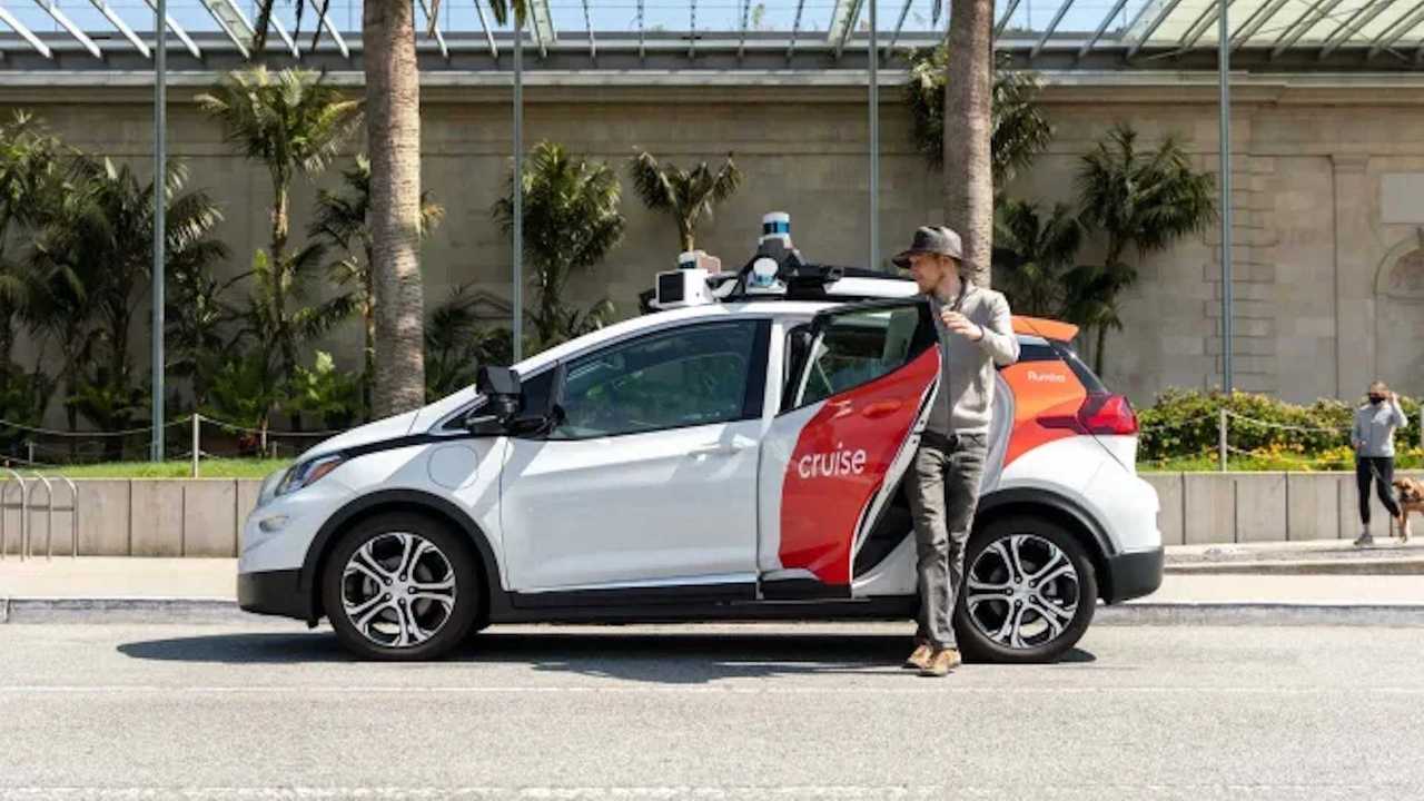 A passenger exits a GM Cruise Driverless Taxi on a sunny street. 